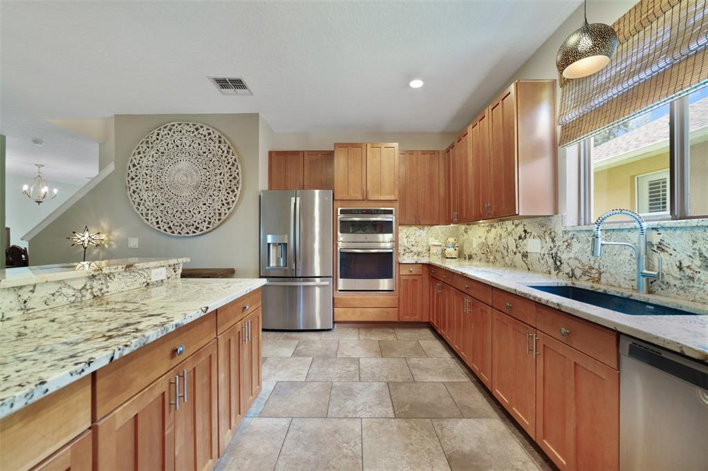 A kitchen features wood cabinets, granite countertops, stainless steel appliances, and tile flooring — 2254 ABEY BLANCO DRIVE, ORLANDO, FL