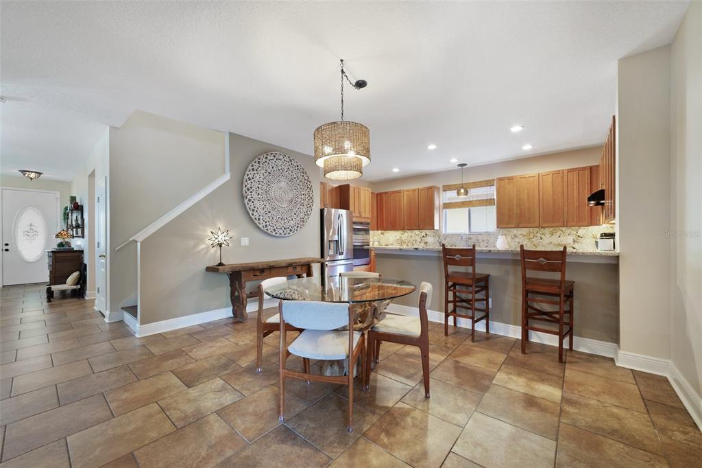 A dining area with a glass table and wooden chairs sits before an open kitchen — 2254 ABEY BLANCO DRIVE, ORLANDO, FL