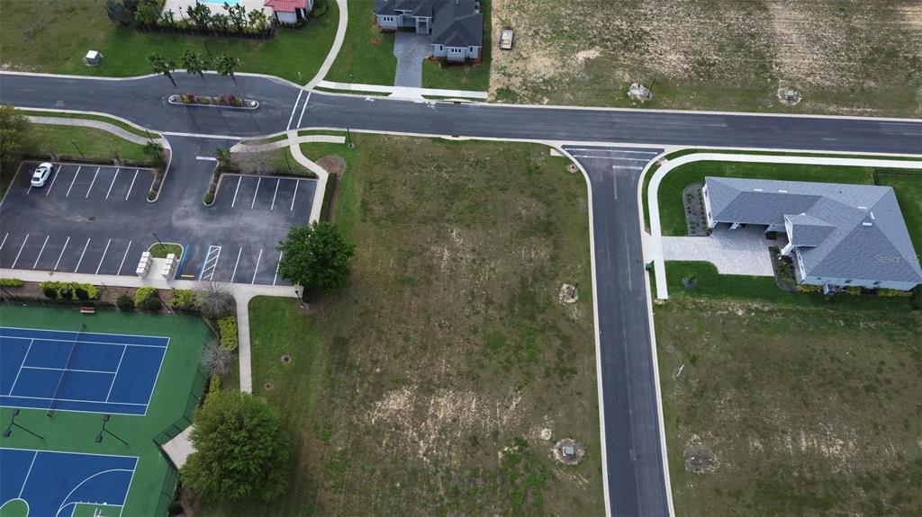 An aerial view shows a vacant residential lot situated between a parking lot and a house — 229 SNOWY ORCHID WAY, LAKE ALFRED, FL