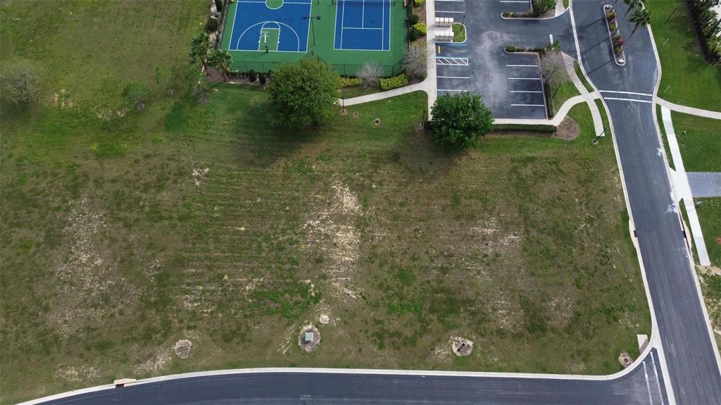 An aerial view of a vacant residential lot adjacent to a parking lot and tennis courts — 229 SNOWY ORCHID WAY, LAKE ALFRED, FL