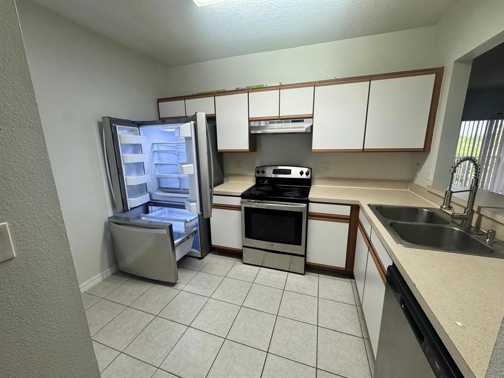 A kitchen with white cabinets, stainless steel appliances, tile flooring, and laminate countertops — 6411 CYPRESSDALE DRIVE UNIT 202, RIVERVIEW, FL