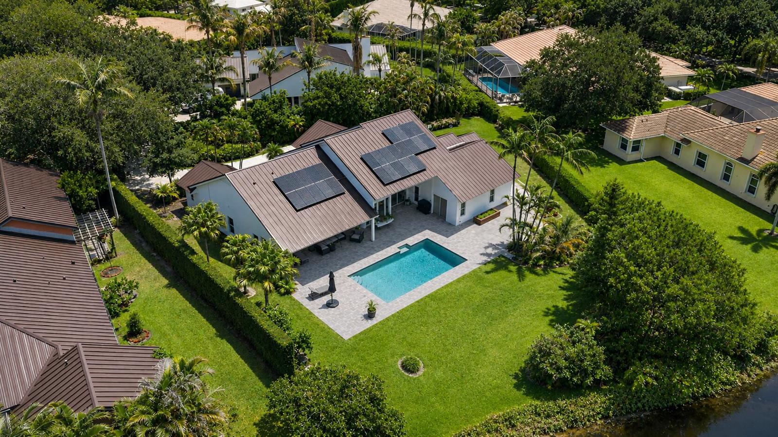 An aerial view of a house with solar panels, a swimming pool, and a backyard — 10290 SE Banyan Way, Jupiter FL 33469, JUPITER, FL
