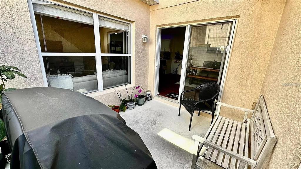 A small concrete patio features a covered grill, a wooden bench, and a black chair — 12621 TANJA KING BOULEVARD, ORLANDO, FL