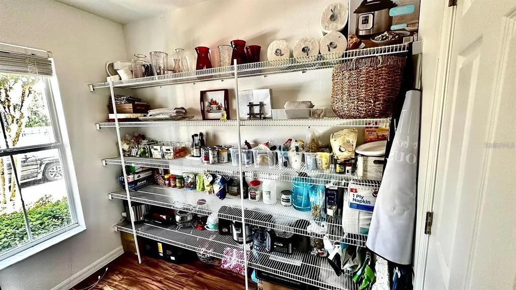 A pantry features white wire shelving units filled with various kitchen items and storage containers — 12621 TANJA KING BOULEVARD, ORLANDO, FL