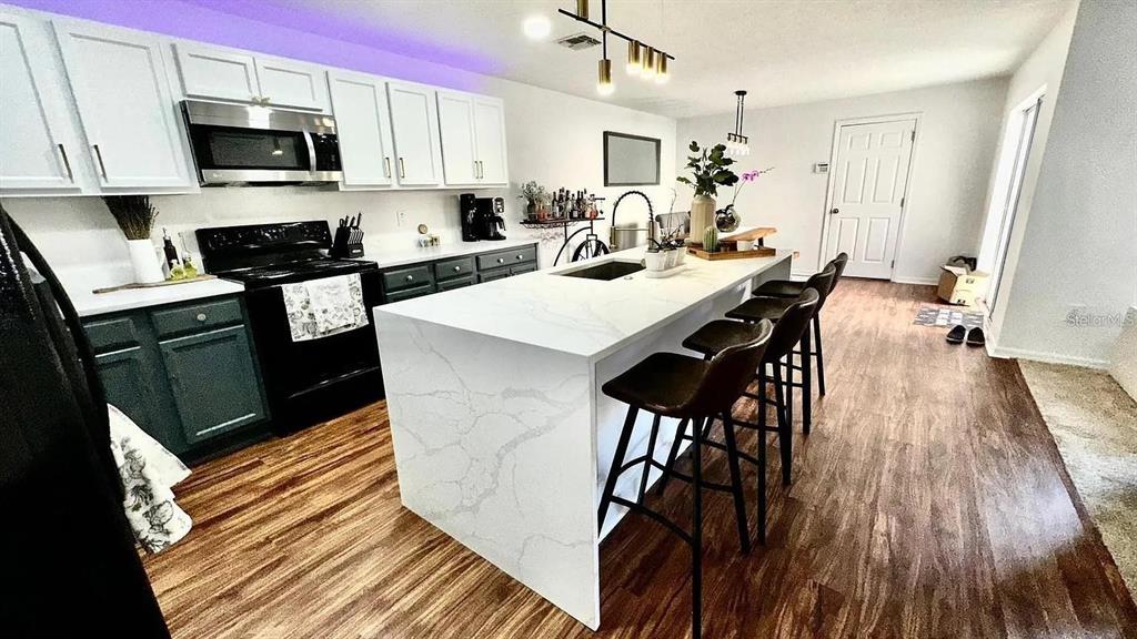 A kitchen features white upper cabinets, dark lower cabinets, and a large white quartz island — 12621 TANJA KING BOULEVARD, ORLANDO, FL