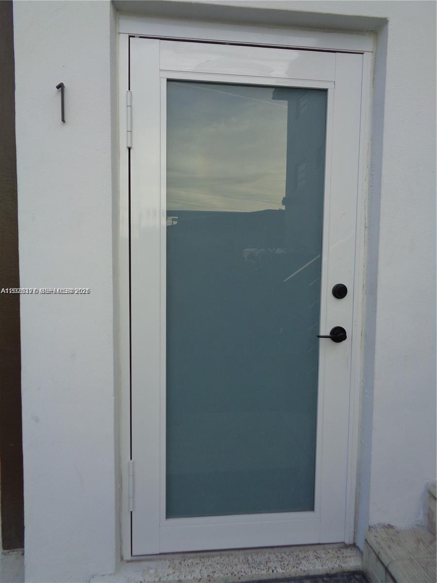 A white door with a large frosted glass panel and black hardware is set in a wall — 2008 SW 3rd St # 1, Miami FL 33135, MIAMI, FL