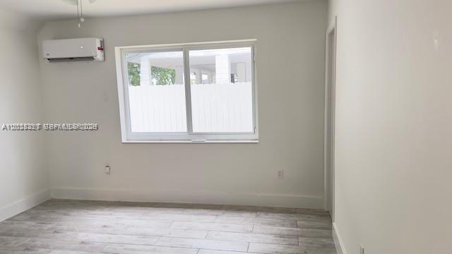 A bedroom with white walls, light wood-look tile flooring, a window, and a wall-mounted air conditioner — 2008 SW 3rd St # 1, Miami FL 33135, MIAMI, FL