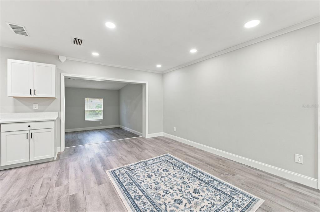 A room with light gray walls, wood-look flooring, recessed lighting, and a white cabinet unit — 7178 HOLIDAY DRIVE, SPRING HILL, FL