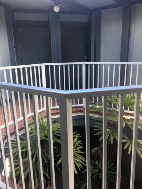 A white metal railing overlooks a small courtyard with palm plants and two dark doors — 3572 SOUTHPOINTE DRIVE UNIT 1, ORLANDO, FL