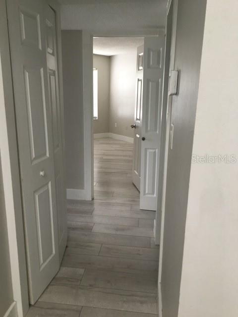 A hallway with light wood-look tile flooring leads to an open doorway into a room — 3572 SOUTHPOINTE DRIVE UNIT 1, ORLANDO, FL