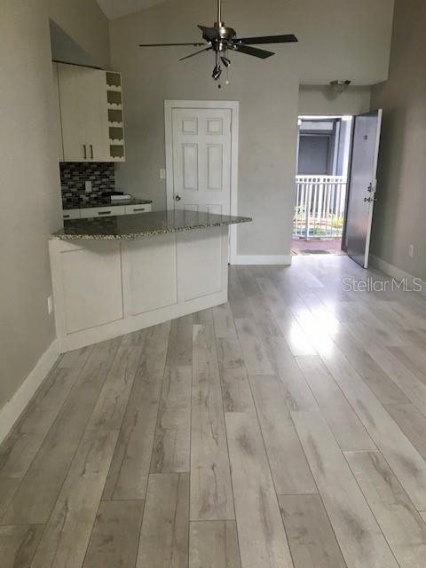 A kitchen with white cabinets and a granite breakfast bar overlooks a light-floored living area — 3572 SOUTHPOINTE DRIVE UNIT 1, ORLANDO, FL