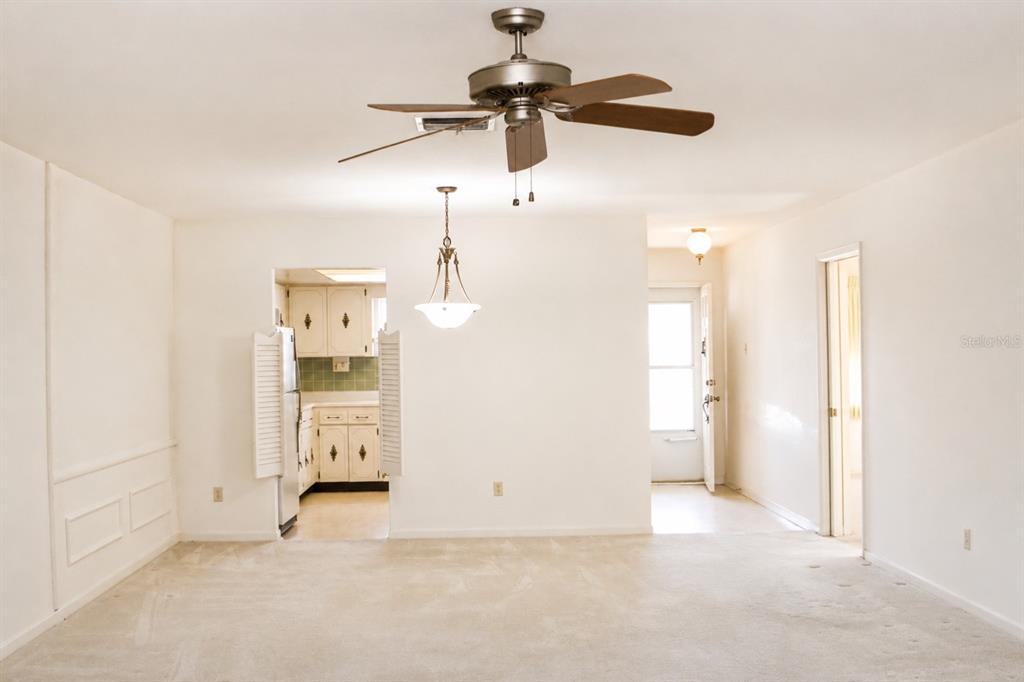 A living room with beige carpet, a ceiling fan, and an adjacent kitchen doorway — 1656 S LAKE AVENUE UNIT 4, CLEARWATER, FL