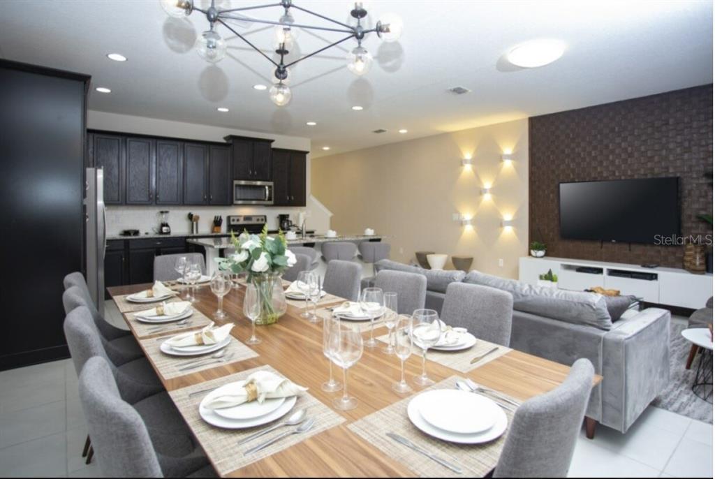 A dining area with a long wooden table opens into a kitchen and living room — 1561 CAREY PALM CIRCLE, KISSIMMEE, FL