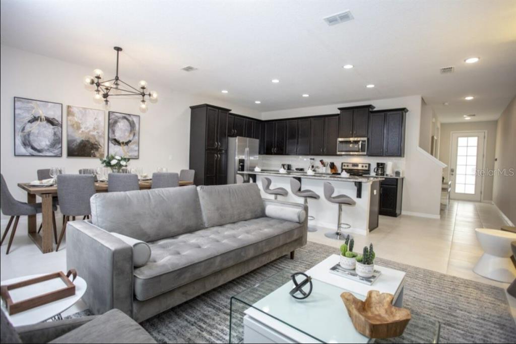 An open-concept living room, dining area, and kitchen with dark cabinets and gray furniture — 1561 CAREY PALM CIRCLE, KISSIMMEE, FL