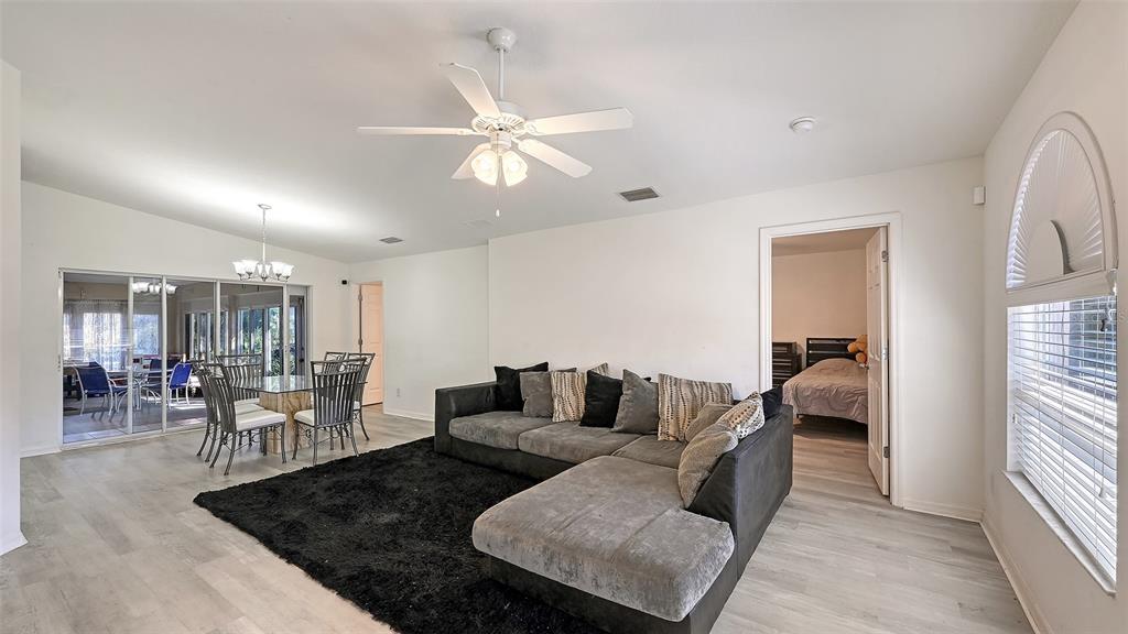 A living room with a gray sectional, black rug, dining area, and ceiling fan — 625 VERROCCHIO DRIVE UNIT 625, NOKOMIS, FL