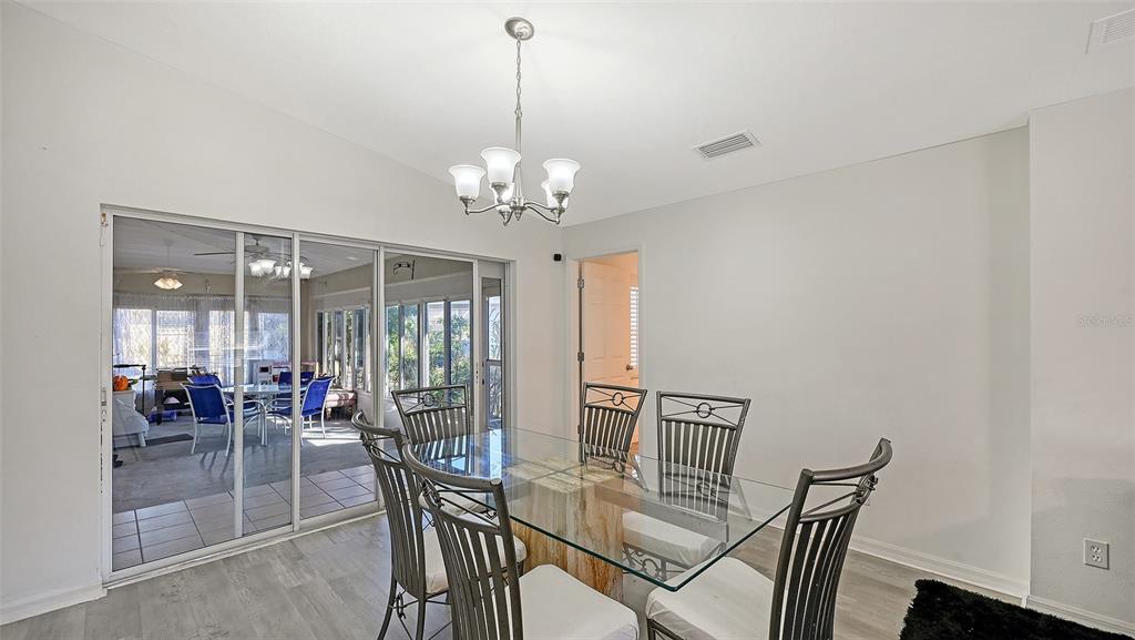 A dining room with a glass-top table, metal chairs, and sliding doors to a patio — 625 VERROCCHIO DRIVE UNIT 625, NOKOMIS, FL
