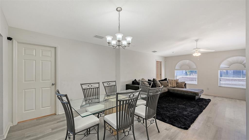 A dining area with a glass table and chairs sits adjacent to a living room — 625 VERROCCHIO DRIVE UNIT 625, NOKOMIS, FL