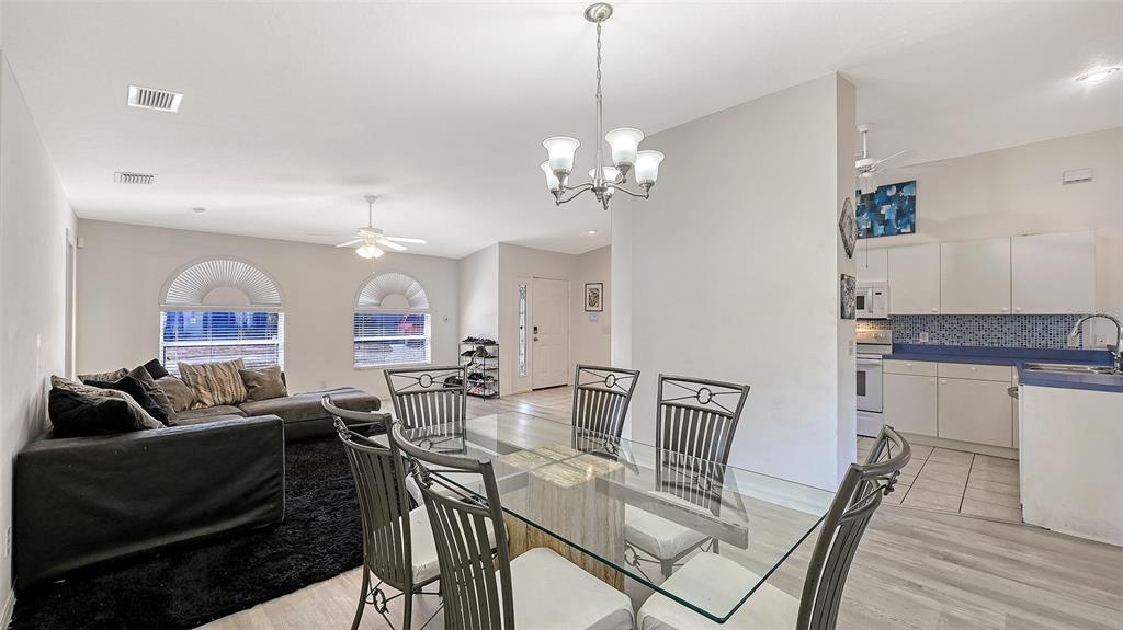 An open-concept living and dining area features a glass table, sofa, and adjacent kitchen — 625 VERROCCHIO DRIVE UNIT 625, NOKOMIS, FL