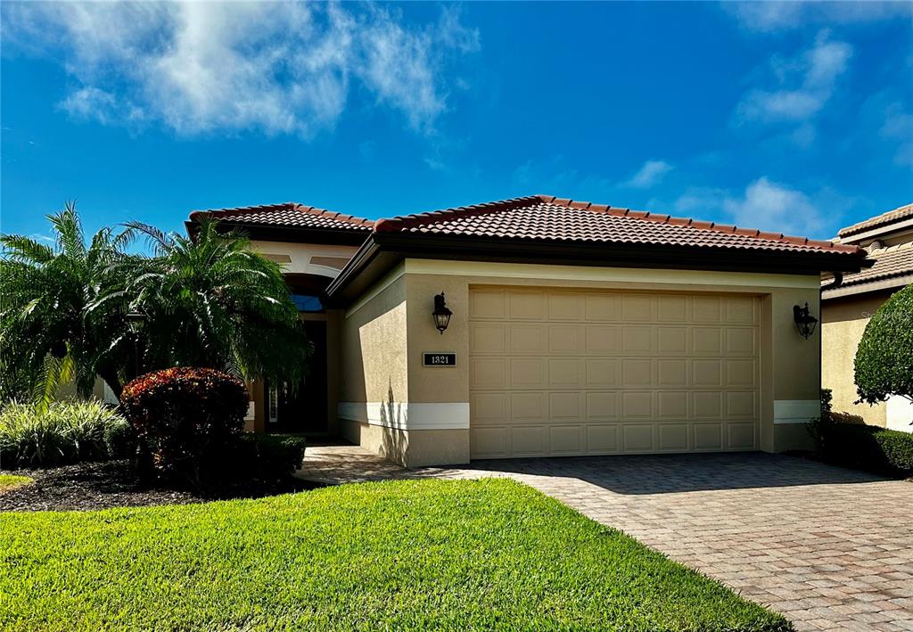 A single-story house with a beige stucco exterior, a tiled roof, and a two-car garage — 1321 CIELO COURT, NOKOMIS, FL