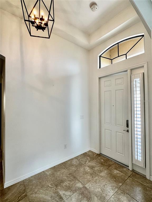 An entryway features a geometric chandelier, tile flooring, a white front door, and a transom window — 1321 CIELO COURT, NOKOMIS, FL