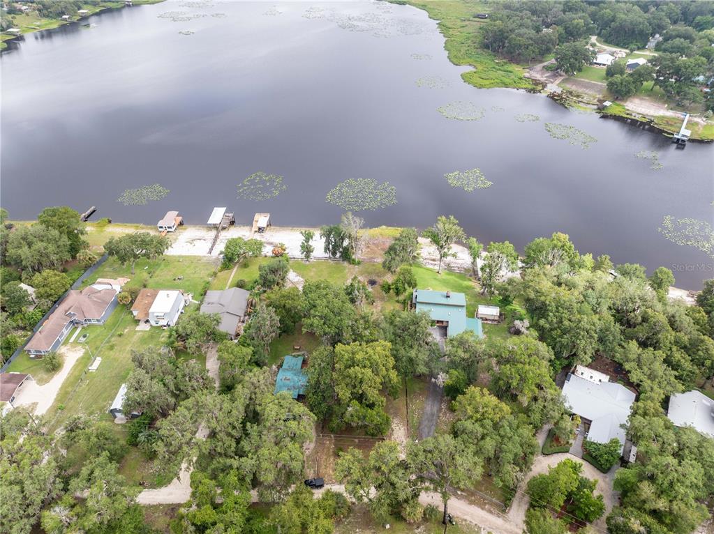 An aerial view shows several houses situated along the grassy shore of a large lake — 114 LITTLE ORANGE LAKE DRIVE, HAWTHORNE, FL