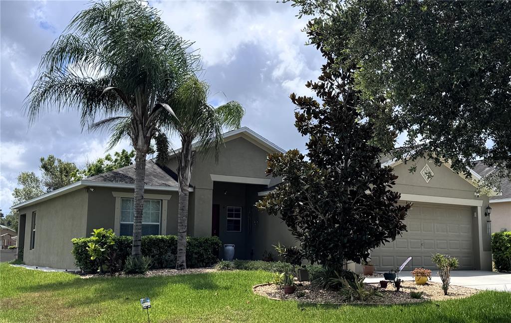 A single-story house with a tan exterior, a two-car garage, and two palm trees — 18722 DOBSON DRIVE, HUDSON, FL