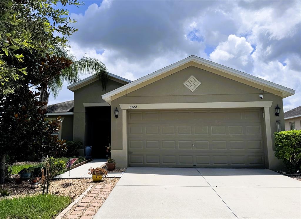 A single-story house features a two-car garage, a concrete driveway, and a tan stucco exterior — 18722 DOBSON DRIVE, HUDSON, FL
