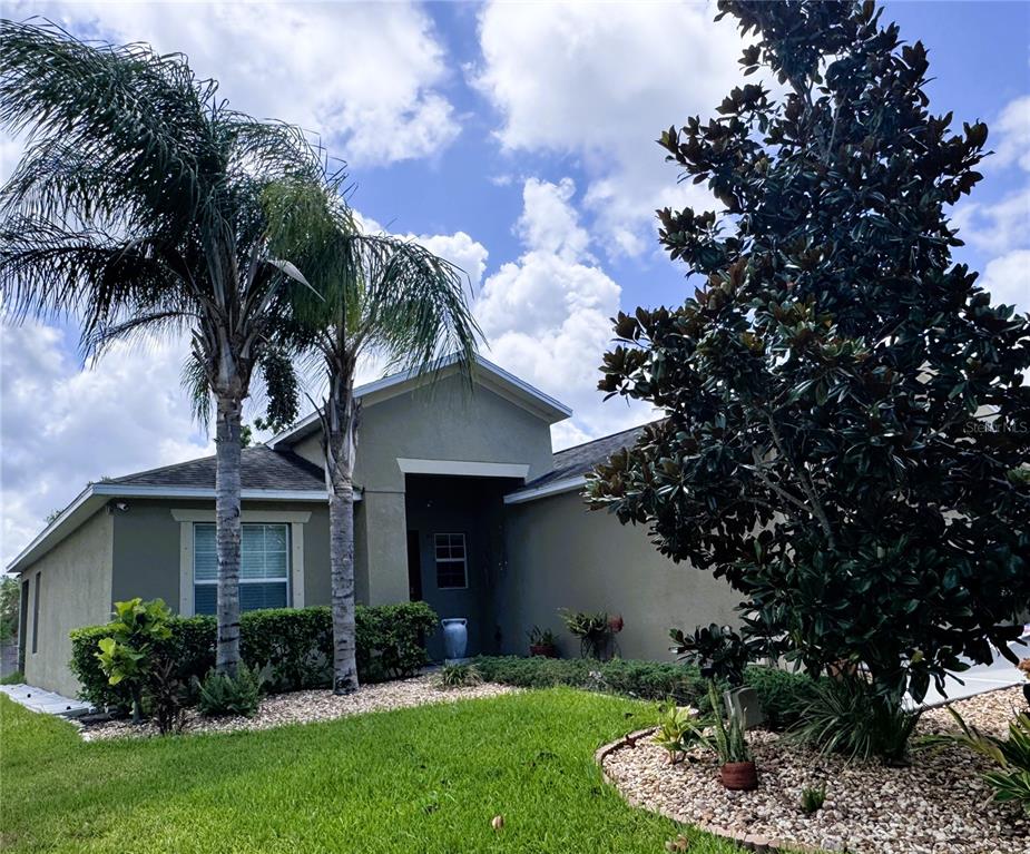 A single-story house with a stucco exterior, palm trees, and a landscaped front yard — 18722 DOBSON DRIVE, HUDSON, FL