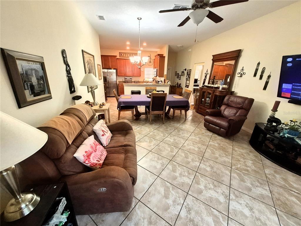 A living room and dining area with tile flooring, brown furniture, and an open kitchen — 18722 DOBSON DRIVE, HUDSON, FL
