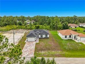 An aerial view shows two single-story suburban houses with paved driveways and surrounding grassy lots — 3310 61st St, Lehigh Acres FL 33971, LEHIGH ACRES, FL