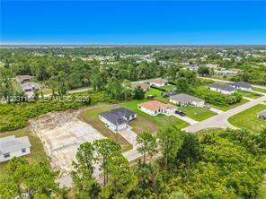 An aerial view shows several suburban houses and a vacant lot surrounded by dense vegetation — 3310 61st St, Lehigh Acres FL 33971, LEHIGH ACRES, FL