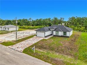 A newly constructed single-story house with a paved driveway sits on a grassy lot — 3310 61st St, Lehigh Acres FL 33971, LEHIGH ACRES, FL