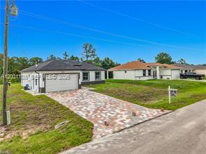 A single-story house with a paved driveway and a two-car garage under a clear sky — 3310 61st St, Lehigh Acres FL 33971, LEHIGH ACRES, FL