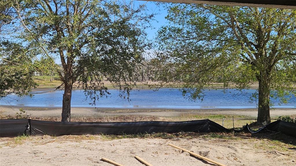 A view of a lake from a sandy construction site with a black silt fence — 9149 TREVINO DRIVE, WEEKI WACHEE, FL