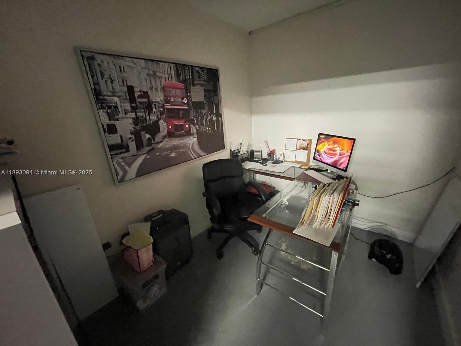 A home office features a glass desk, a black chair, and a large London-themed wall art — 10820 NW 138th St # C, Hialeah Gardens FL 33018, HIALEAH GARDENS, FL