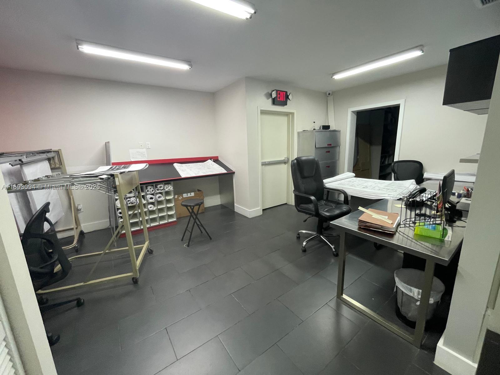 An office space features a drafting table, a desk, and gray tile flooring — 10820 NW 138th St # C, Hialeah Gardens FL 33018, HIALEAH GARDENS, FL
