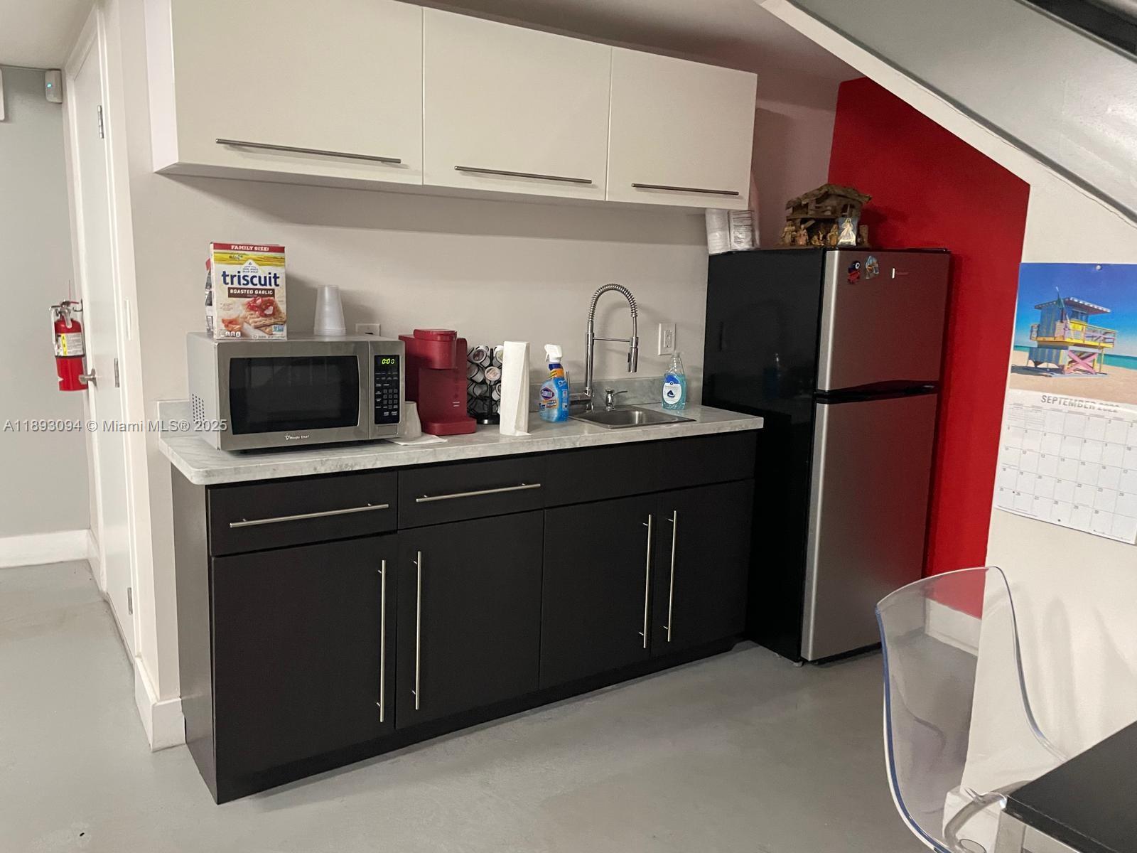 A small kitchenette features dark lower cabinets, white upper cabinets, a microwave, and a refrigerator — 10820 NW 138th St # C, Hialeah Gardens FL 33018, HIALEAH GARDENS, FL