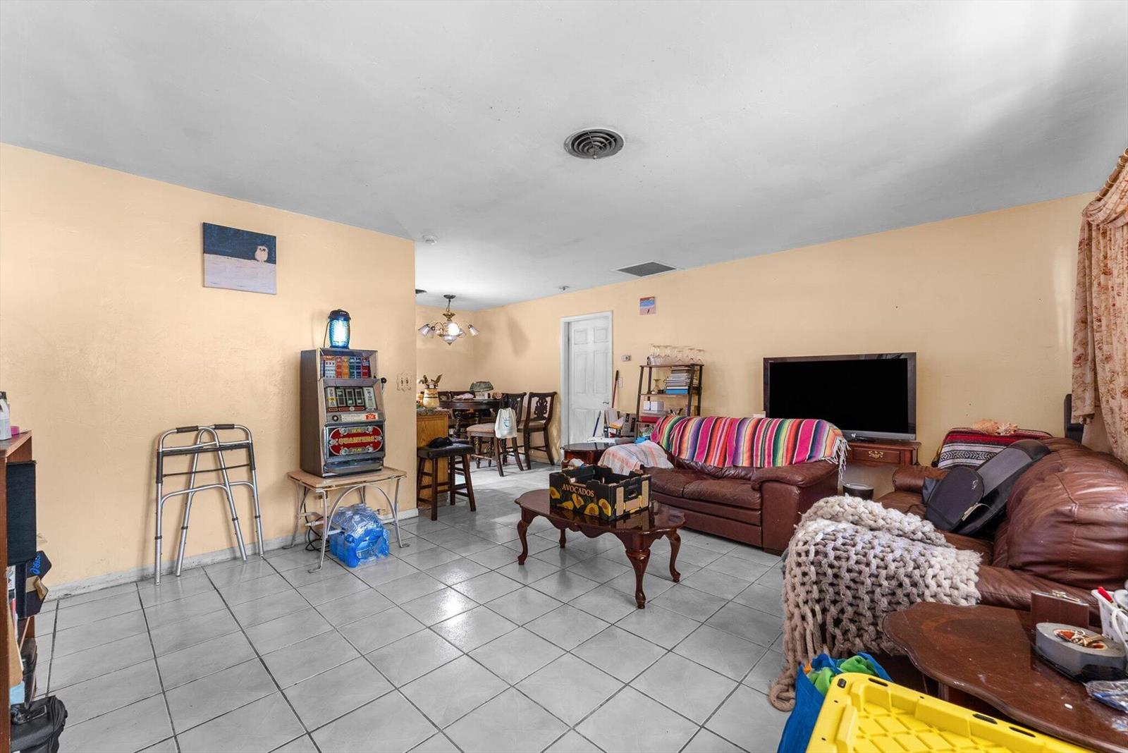 A living room with tile flooring, a brown leather sofa, and a vintage slot machine — 2106 WARE Drive, West Palm Beach FL 33409, WEST PALM BEACH, FL
