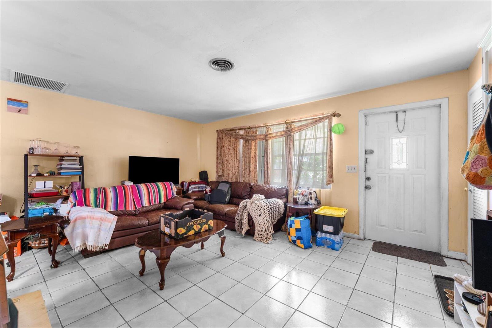 A living room features tile flooring, a brown leather sofa, and a white front door — 2106 WARE Drive, West Palm Beach FL 33409, WEST PALM BEACH, FL