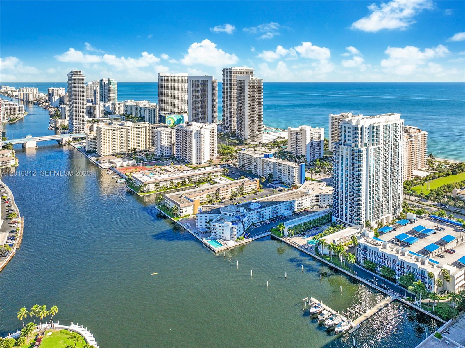 An aerial view shows high-rise residential buildings along a waterway and the ocean coast — 1945 S Ocean Dr # 1609, Hallandale Beach FL 33009, HALLANDALE BEACH, FL