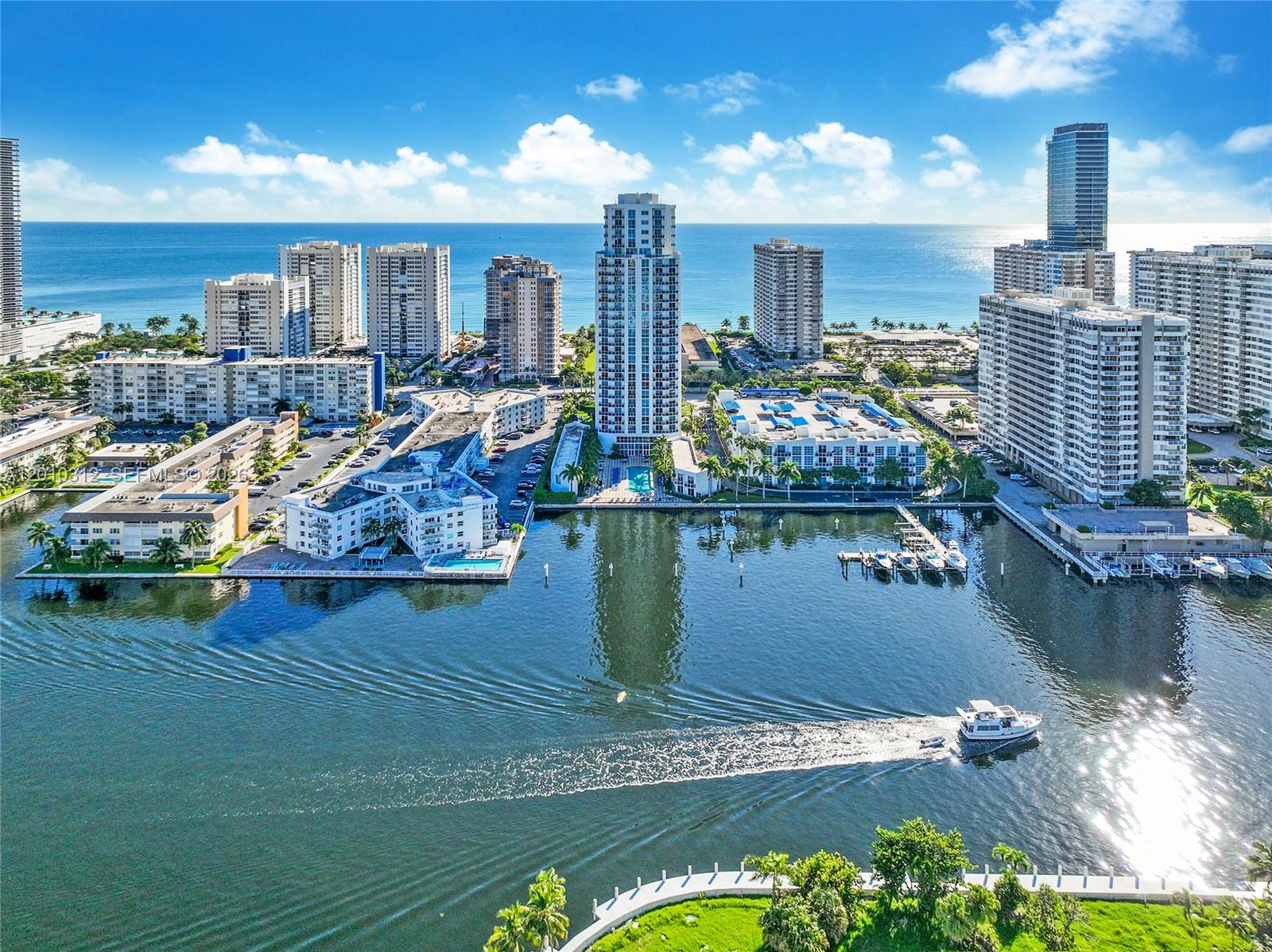 An aerial view shows a coastal city with high-rise buildings, a waterway, and a boat — 1945 S Ocean Dr # 1609, Hallandale Beach FL 33009, HALLANDALE BEACH, FL