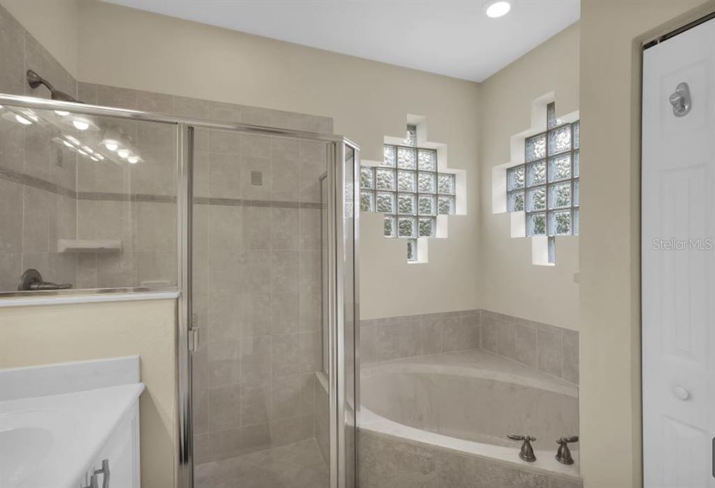 A bathroom features a glass-enclosed shower, a corner soaking tub, and decorative glass block windows — 90 W WATERSIDE PARKWAY, PALM COAST, FL