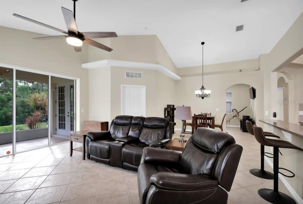 A living room with tile floors, a vaulted ceiling, leather furniture, and a dining area — 90 W WATERSIDE PARKWAY, PALM COAST, FL
