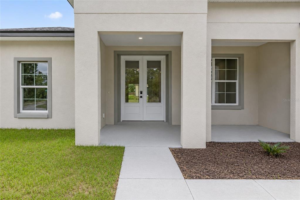 The exterior of a house features a concrete walkway leading to white double front doors — 7295 N GLENRIDGE CIRCLE, CITRUS SPRINGS, FL