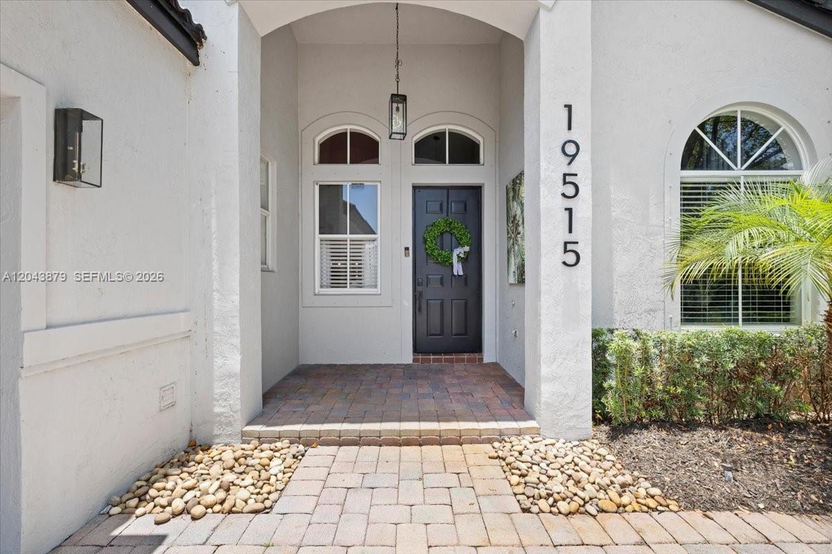 The front entrance features a dark door with a wreath, stone walkway, and house numbers — 19515 SW 25th Ct, Miramar FL 33029, MIRAMAR, FL