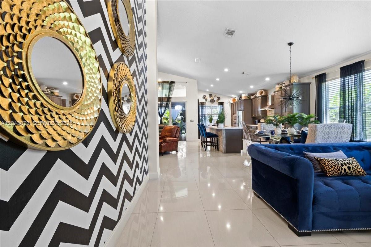 A living room features a chevron-patterned wall with gold mirrors and a blue sofa — 19515 SW 25th Ct, Miramar FL 33029, MIRAMAR, FL