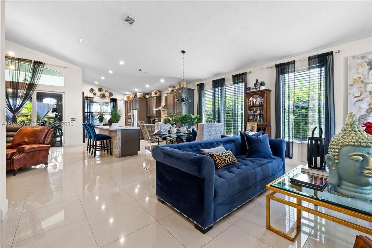 An open-concept living and dining area features white tile floors and a blue velvet sofa — 19515 SW 25th Ct, Miramar FL 33029, MIRAMAR, FL