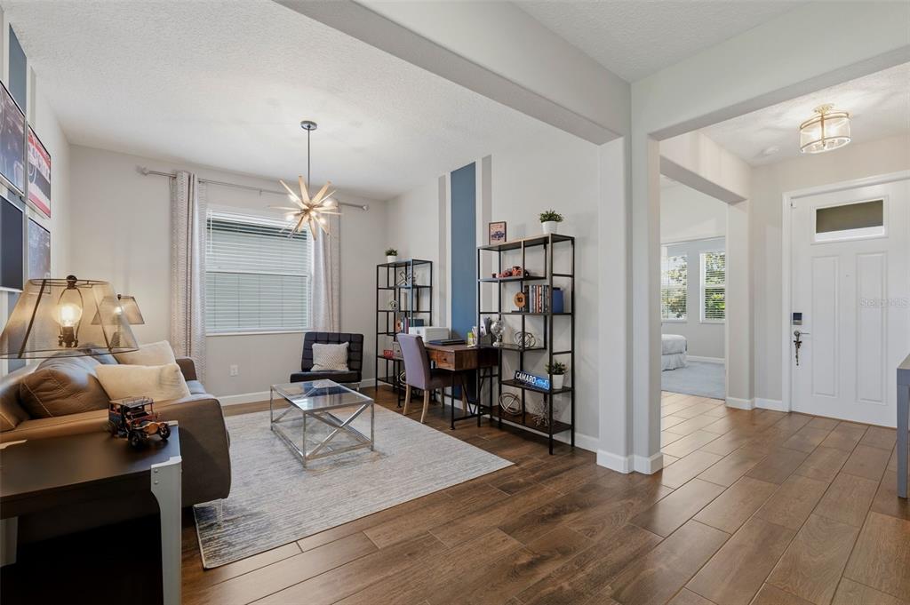 A living room features a brown sofa, a glass coffee table, and wood-look tile flooring — 31700 CANNON RUSH DRIVE, SAN ANTONIO, FL