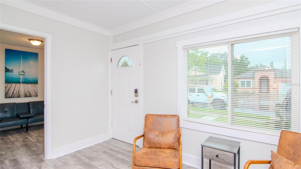 A living area features light gray flooring, white walls, two leather chairs, and a front door — 1466 LAURA STREET, CLEARWATER, FL