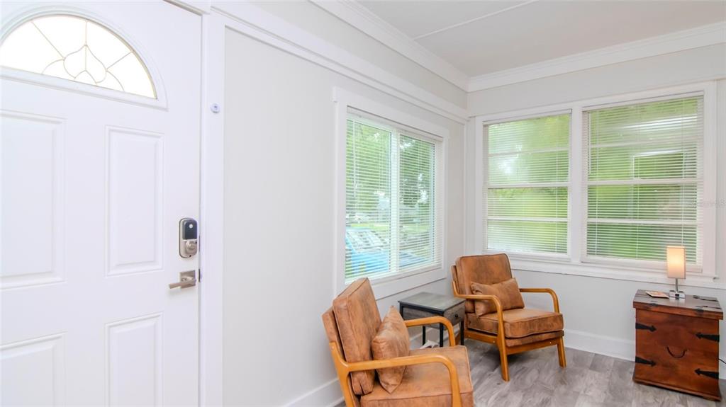 A sunroom features two leather armchairs, a side table, and a wooden chest near windows — 1466 LAURA STREET, CLEARWATER, FL